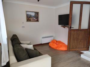 a living room with a couch and a flat screen tv at Терасите - Къща 4 in Ribarica