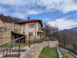 a house with a stone wall next to a building at Терасите - Къща 4 in Ribarica