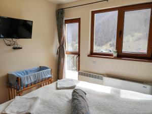 Schlafzimmer mit einem Bett, einem TV und Fenstern in der Unterkunft Терасите - Къща 4 in Ribarica