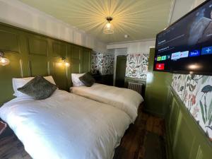 two beds in a room with a flat screen tv at The Dundrum Inn B&B in Dundrum