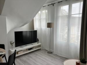 uma sala de estar com uma televisão de ecrã plano num armário branco em Appart Cozy CDG, Paris, Disney, Parc Expo, Astérix em Dammartin-en-Goële