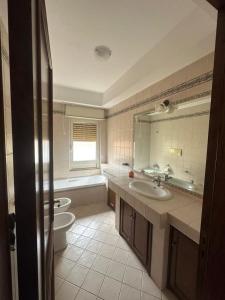 łazienka z 2 umywalkami, toaletą i wanną w obiekcie Appartamento Cocò w mieście Praia a Mare
