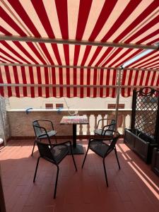 a patio with a table and chairs and a red and white striped ceiling at B&B Centro Storico in Diamante