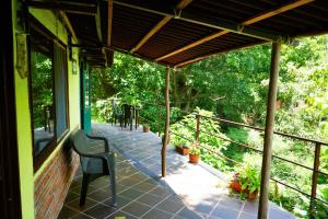 a porch of a house with a chair and trees at Romeo y Julieta, cabaña privada en Minca in Minca