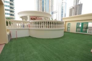 uma varanda de um edifício com um relvado verde em Budget Rooms With Private Bathroom for 'girls' only in Dubai, Marina em Dubai