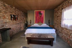 1 dormitorio con cama y pared de ladrillo en The Desert House en Uis