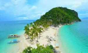 an island with palm trees and boats on a beach at Ludy's 2 Pension House in Carles