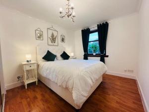 um quarto com uma cama, uma janela e um lustre em A Stylish Two-Bedroom Flat-Free Parking-CityCentre em Aberdeen
