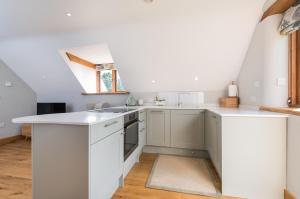 uma cozinha com armários brancos e uma janela em Exquisite Coach House Near Silverstone & Stowe em Buckingham