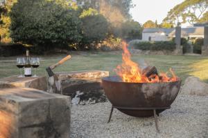 a fire pit with a bowl and glasses of wine at Alba House in Robertson