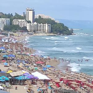 a crowded beach with people and umbrellas and the ocean at Ваканционни къщи'На брега' Holiday houses ON THE COAST in Varna City