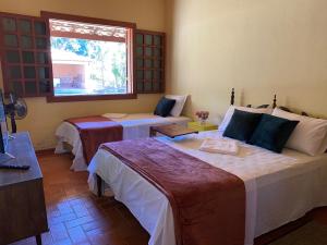 a bedroom with two beds and a window at Hospedaria Casa dos Coqueiros in Itabirito