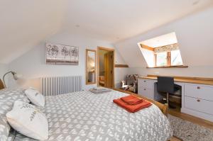 a bedroom with a bed and a desk with a computer at Exquisite Coach House Near Silverstone & Stowe in Buckingham