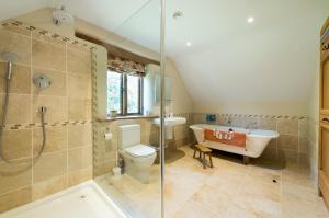 Exquisite Coach House Near Silverstone & Stowe في باكنغهام: حمام مع مرحاض وحوض استحمام ومغسلة