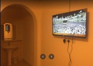 baño con TV de pantalla plana en la pared en Zahret Al Madinah en Medina