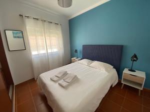sypialnia z białym łóżkiem i 2 ręcznikami w obiekcie Apartamento Vicentino w mieście Vila Nova de Milfontes