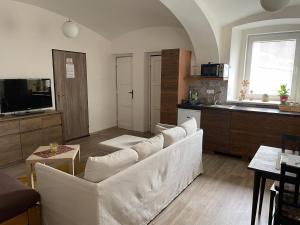 a living room with a white couch and a kitchen at Rodinný apartmán Mariánská in Varnsdorf