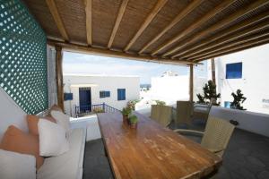 eine Terrasse mit einem Holztisch und Stühlen auf dem Balkon in der Unterkunft Hibiscus Rosa Mykonos in Mykonos Stadt