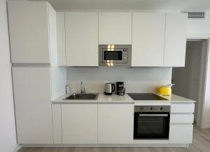 uma cozinha branca com um lavatório e um micro-ondas em Haus Margarete - Agenzia Cocal em Caorle