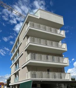 a tall apartment building with white balconies on it at Haus Margarete - Agenzia Cocal in Caorle