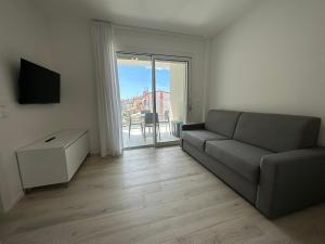 uma sala de estar com um sofá e uma porta de vidro deslizante em Haus Margarete - Agenzia Cocal em Caorle