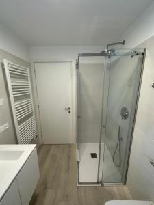 uma casa de banho com um chuveiro e uma porta de vidro em Haus Margarete - Agenzia Cocal em Caorle