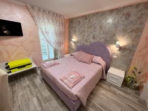 um pequeno quarto com uma cama rosa e uma janela em VittoNico em Morcone