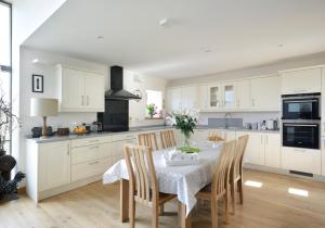 a kitchen with white cabinets and a table with chairs at Osprey Lodge in Kingussie +13 photos