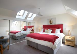 a bedroom with two beds and a red headboard at Osprey Lodge in Kingussie