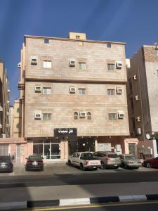 un gran edificio con coches estacionados frente a él en Al asalah apartments, en La Meca