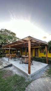 a wooden pavilion with a picnic table in front of a yellow building at Hotel Urumajó in Augusto Correa