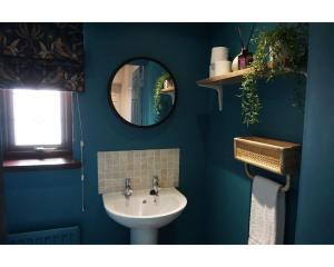 bagno blu con lavandino e specchio di Central Belfast Apartments The Village House a Belfast