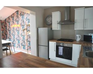 a kitchen with white appliances and a table and a dining room at Central Belfast Apartments The Village House in Belfast