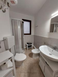a white bathroom with a toilet and a sink at la chiocciola in Mesagne