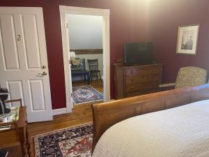 Schlafzimmer mit einem Bett, einem TV und einer Tür in der Unterkunft Dodds Brick House Bed & Breakfast in North Hero