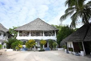 ein weißes Gebäude mit einem Strohdach in der Unterkunft Ananda Villa Zanzibar in Bwejuu