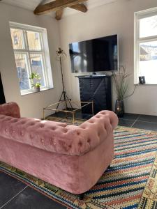 a pink couch in a living room with a tv at Villa Deluxe at Brohuspark in Lomma