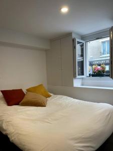 1 cama blanca con 2 almohadas y ventana en Heart of Paris Apartment en París