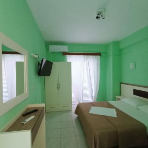 a green bedroom with a bed and a tv at Casa Angelina in Polychrono