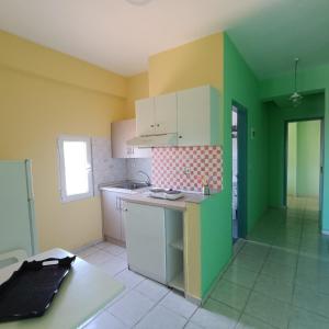 a kitchen with green and yellow walls and white cabinets at Casa Angelina in Polychrono