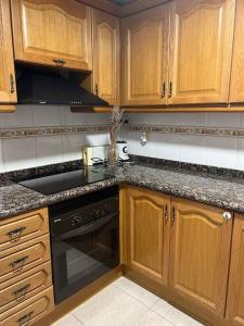 een keuken met houten kasten en een zwarte kookplaat bij Puerto Romano Denia in Denia +3 foto's