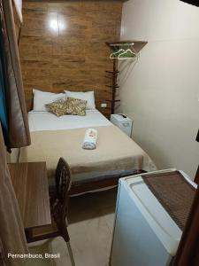 a small bedroom with a bed and a table at Florcamará POUSADA in Camaragibe