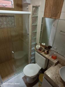 a bathroom with a toilet and a glass shower at Florcamará POUSADA in Camaragibe