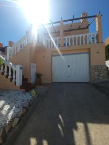 a house with a garage with the sun shining on it at Chalet Edy con piscina in Peniscola