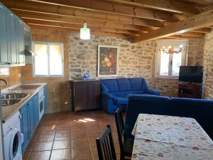 sala de estar con sofá azul y cocina en Piedra Dorada en Pereruela