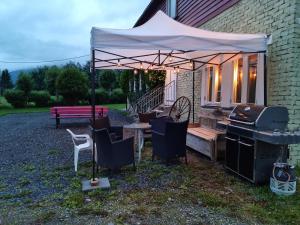 a barbecue under a tent next to a house at Rødseth gårdsovernatting Hytter in Molde