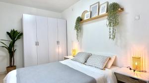 1 dormitorio con 1 cama con 2 almohadas y plantas en Cozy 2 bedroom apartment in Nahariya, en Nahariyya