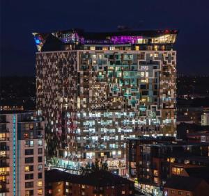 a tall building with lights on top of it at night at The Cube Side Apartments - One Bedroom With Balcony in Birmingham