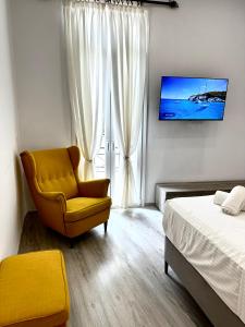 Un dormitorio con una silla amarilla y una cama en Travelers Luxury Suites, Studios & Apartments en Agios Rokkos