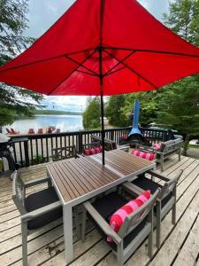 una mesa de madera con una sombrilla roja en una terraza en Willow Cabin- North Frontenac Lodge en Ompah